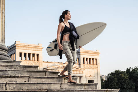 Young woman with surfboard on the way to Eisbach, Munich, Germany stock photo