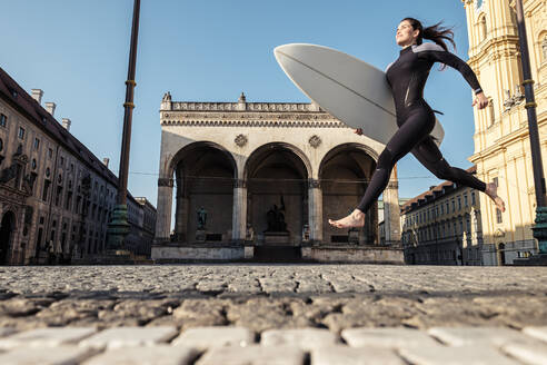 Young woman with surfboard on the way to Eisbach, Munich, Germany - WFF00189