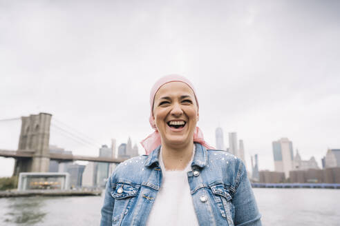Porträt einer lachenden Frau mit Krebstuch an der Brooklyn Bridge in New York, USA - DAMF00222