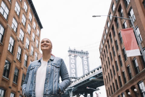 Lächelnde Frau mit Krebstuch an der Manhattan Bridge in New York, USA, lizenzfreies Stockfoto