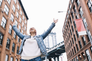 Frau mit Krebstuch und erhobenen Armen an der Manhattan Bridge in New York, USA - DAMF00225