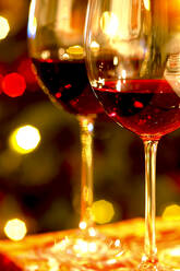 Germany, Two glasses of red wine and Christmas lights - JTF01430