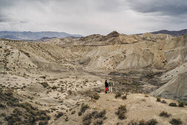 Junges Paar in Wüstenlandschaft unter bewölktem Himmel, Almeria, Andalusien, Spanien - MPPF00246