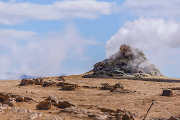 Hillside landscape with rock formation and rising steam against blue sky, Akureyri, Eyjafjardarsysla, Iceland - CUF53479