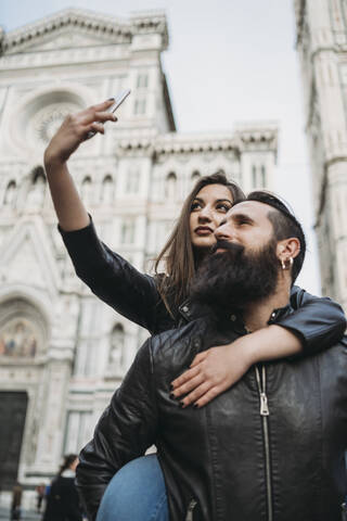 Paar spielt Huckepack und macht ein Selfie, Santa Maria del Fiore, Florenz, Toskana, Italien, lizenzfreies Stockfoto