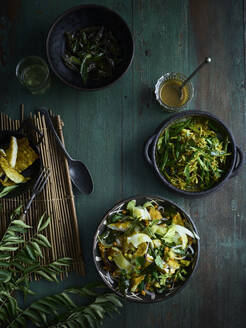 Rustikales Stilleben mit Schalen von Curryblattsalat und grünem Bohnenthoran auf dem Tisch, Draufsicht - ISF22829