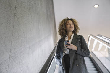 Woman holding cell phone on escalator - AHSF01269