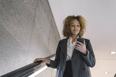 Woman using cell phone on escalator - AHSF01271