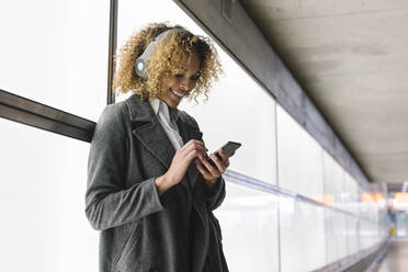 Smiling woman with headphones and smartphone - AHSF01272