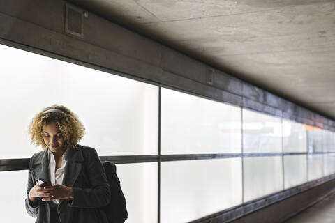 Frau mit Kopfhörern und Smartphone, lizenzfreies Stockfoto