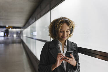 Smiling woman with headphones and smartphone - AHSF01284