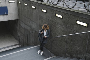 Woman using smartphone at the entrance of a subway station, Berlin, Germany - AHSF01288