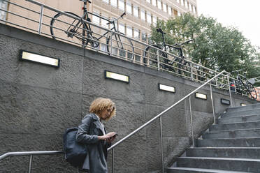 Woman using smartphone at the entrance of a subway station, Berlin, Germany - AHSF01289