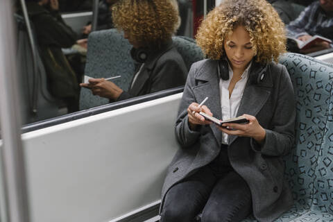 Frau macht Notizen in einer U-Bahn, lizenzfreies Stockfoto