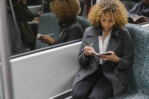 Woman taking notes on a subway stock photo