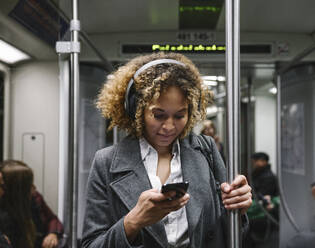 Frau benutzt Smartphone in einer U-Bahn - AHSF01301