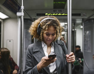 Woman using smartphone on a subway - AHSF01301