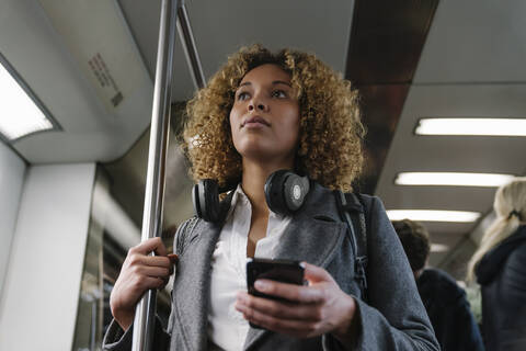 Frau mit Smartphone in einer U-Bahn, lizenzfreies Stockfoto