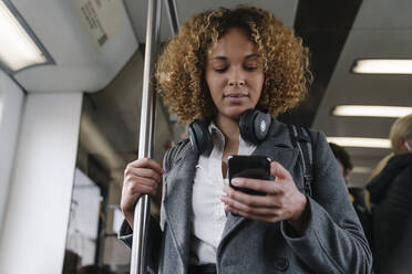 Woman using smartphone on a subway - AHSF01308