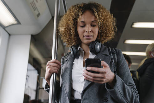 Frau benutzt Smartphone in einer U-Bahn - AHSF01308