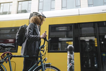 Woman commuting with a bicycle in the city, Berlin, Germany - AHSF01319