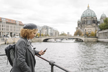 Tourist woman using smartphone in the city with Berlin Cathedral in background, Berlin, Germany - AHSF01326