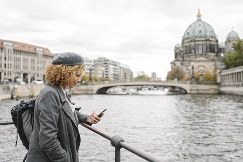 Touristin mit Smartphone in der Stadt mit dem Berliner Dom im Hintergrund, Berlin, Deutschland - AHSF01326