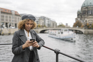 Touristin mit Smartphone in der Stadt mit dem Berliner Dom im Hintergrund, Berlin, Deutschland - AHSF01327