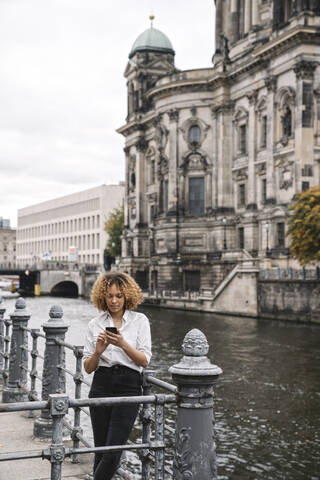 Tourist woman using smartphone in the city at Spree river, Berlin, Germany stock photo