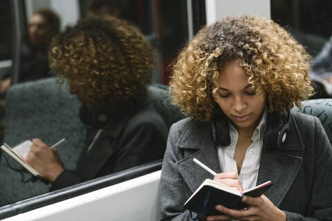 Frau macht Notizen in einer U-Bahn, lizenzfreies Stockfoto