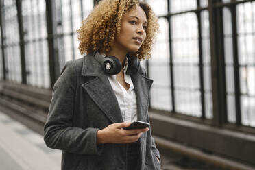 Frau mit Mobiltelefon wartet in der U-Bahn-Station - AHSF01344