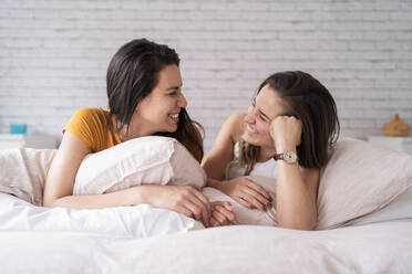 Glückliches lesbisches Paar im Bett liegend - FBAF00943