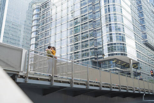 Lesbian couple hugging on a bridge in the city, London, UK - FBAF00974