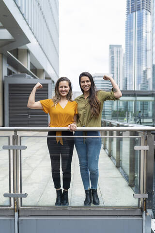 Porträt eines glücklichen lesbischen Paares beim Muskeltraining in der Stadt, London, UK, lizenzfreies Stockfoto