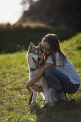 Young woman hugging her dog on a meadow - MAUF03082