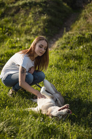 Portrait of young woman stroking her dog on a meadow stock photo