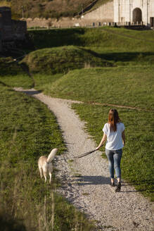 Rückenansicht einer jungen Frau, die mit ihrem Hund Gassi geht - MAUF03091