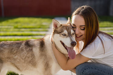 Happy young woman cuddling her dog - MAUF03096