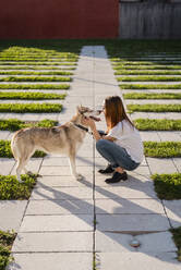 Young woman cuddling her dog outdoors - MAUF03097