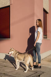 Porträt einer jungen Frau, die abends mit ihrem Hund Gassi geht - MAUF03101
