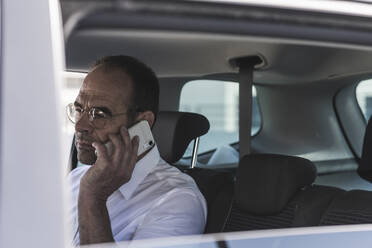 Portrait of mature businessman on the phone in car - UUF19724