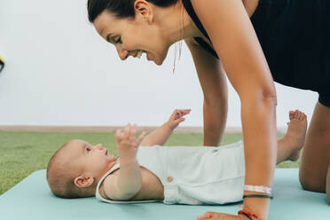 Junge Mutter und Baby beim Üben auf der Yogamatte - MPPF00276