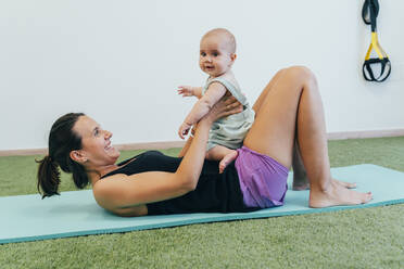 Young mother and baby exercising on yoga mat - MPPF00280