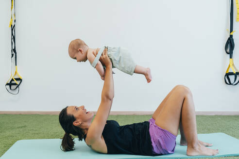 Junge Mutter und Baby beim Üben auf der Yogamatte - MPPF00281