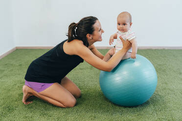 Young mother and baby exercising on fitness ball - MPPF00290