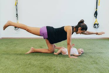 Junge Mutter und Baby trainieren auf grünem Teppich - MPPF00292