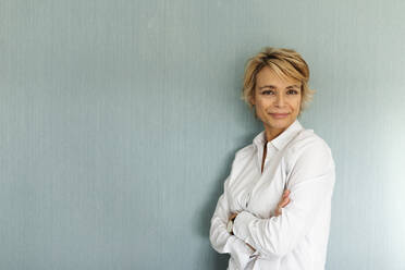 Portrait of confident mature woman standing at a wall - VABF02361