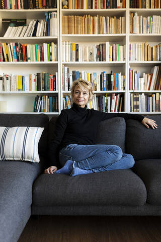 Porträt einer reifen Frau, die sich zu Hause auf der Couch entspannt, lizenzfreies Stockfoto