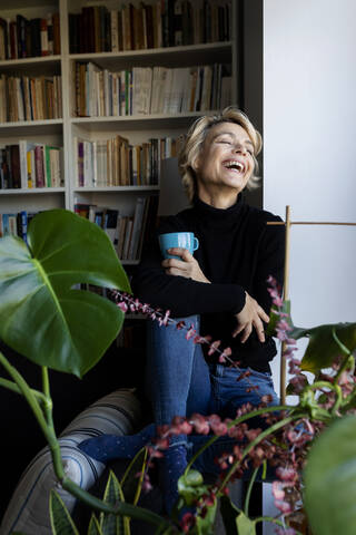 Glückliche reife Frau trinkt Kaffee und entspannt sich zu Hause, lizenzfreies Stockfoto