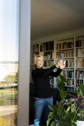 Glückliche reife Frau nimmt ein Selfie zu Hause, lizenzfreies Stockfoto